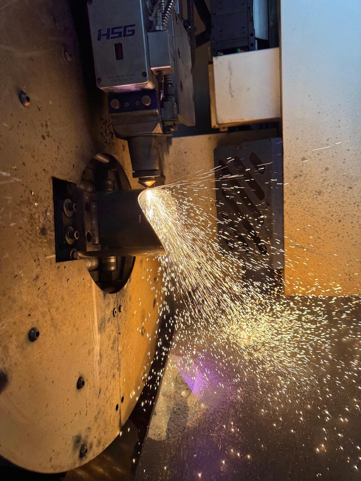 Maszyna tnąca stalową rurę laserem – precyzyjna obróbka metalu z iskrami podczas cięcia